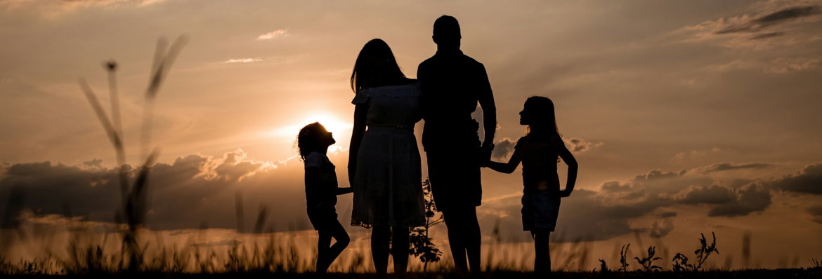 a family standing in a field at sunset